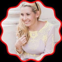 A white woman with blonde hair looks off camera, smiling.